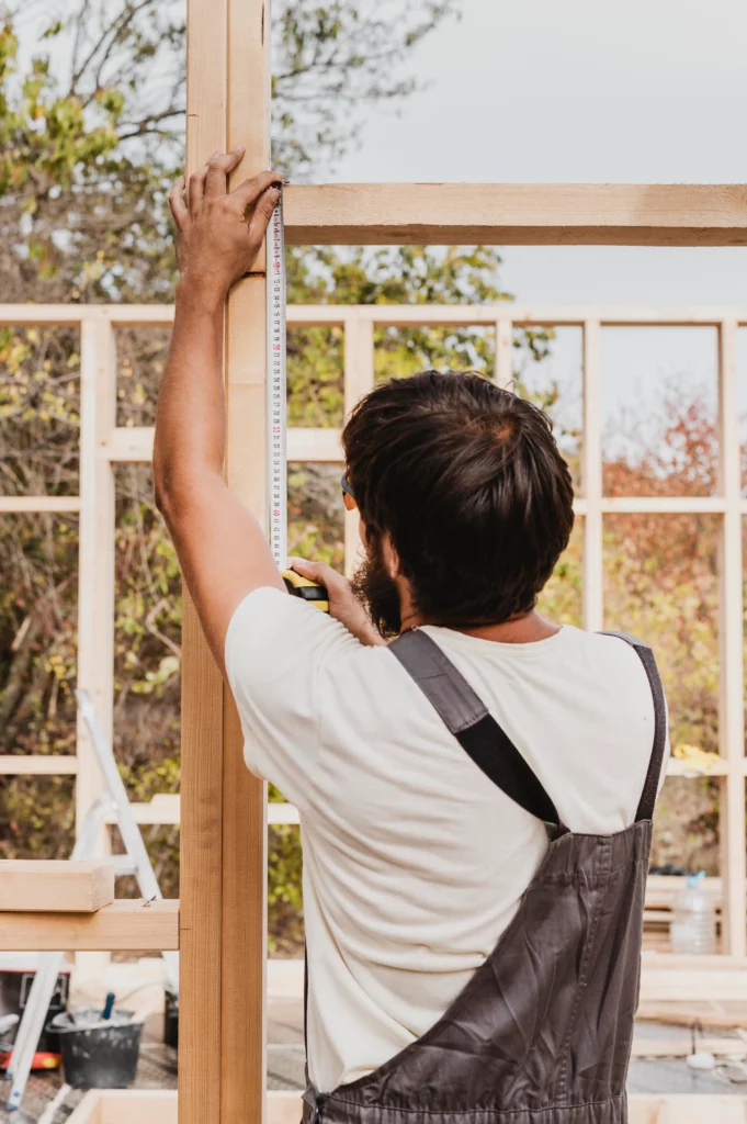 carpenter man using tape measure from shot